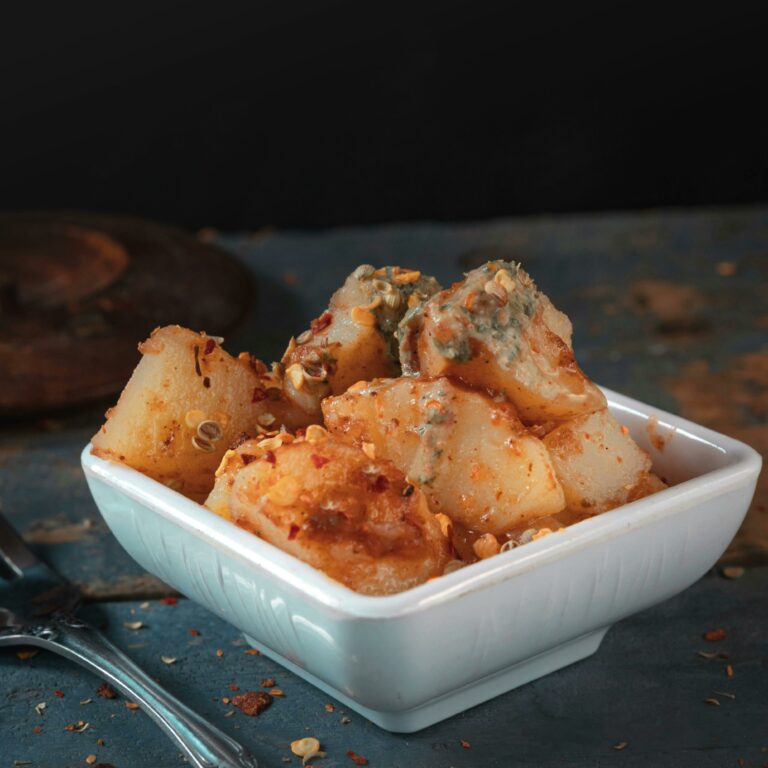 Delicious spicy roasted potatoes served in a white square bowl perfect for a flavorful meal.